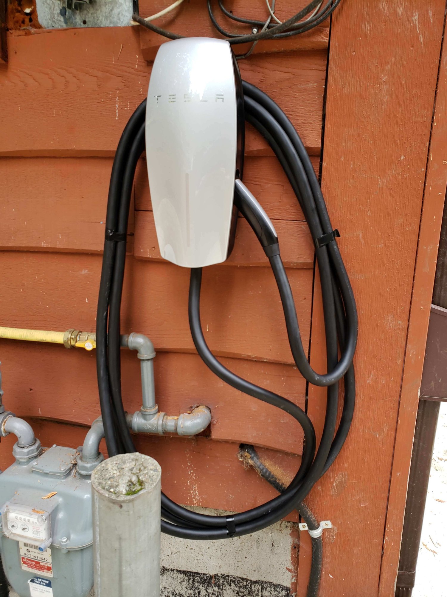 Tesla EV charger installed on outside of house
